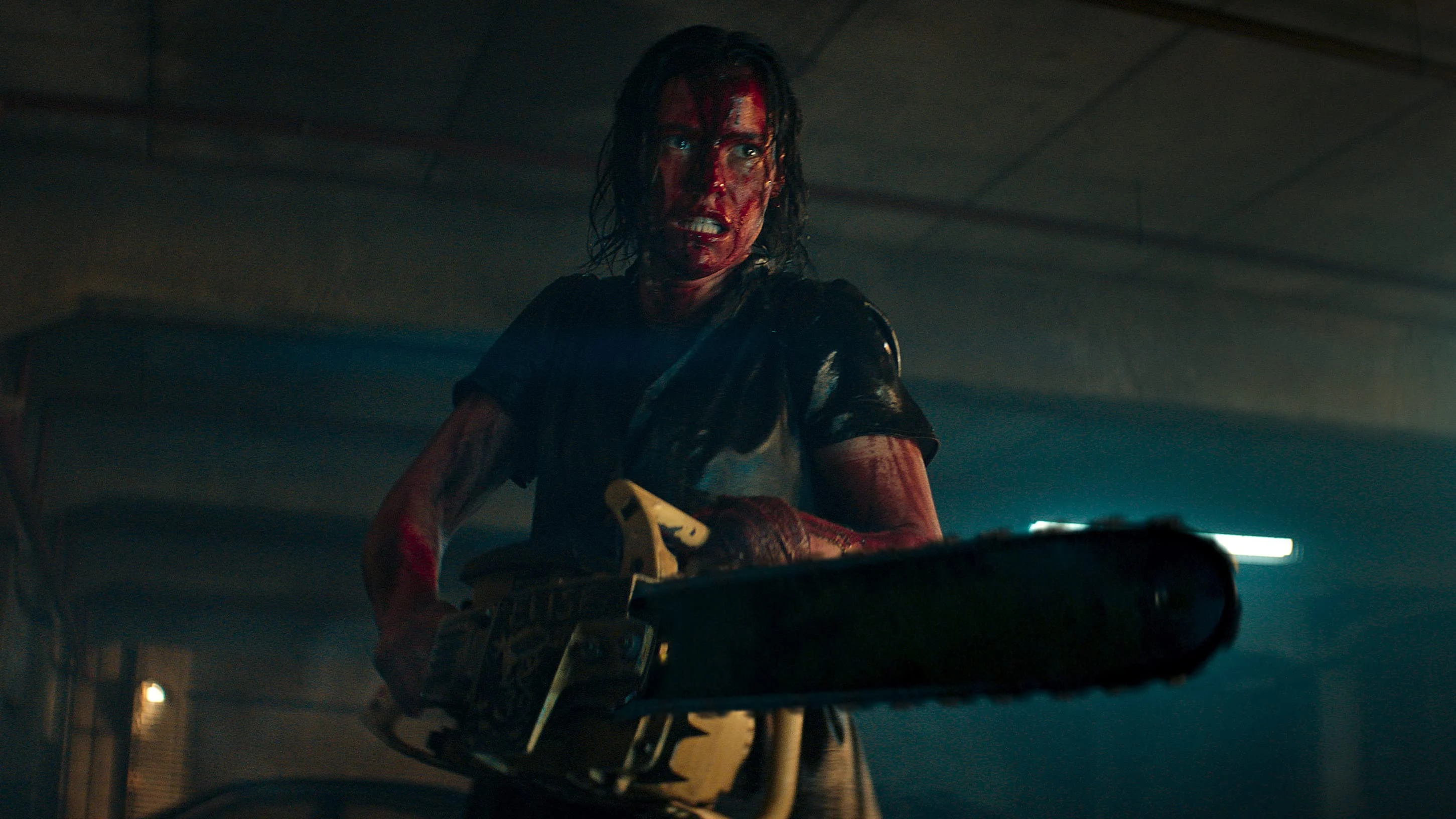 Lily Sullivan as Bethany “Beth” Bixler covered in blood and wielding a chainsaw in Evil Dead Rise.