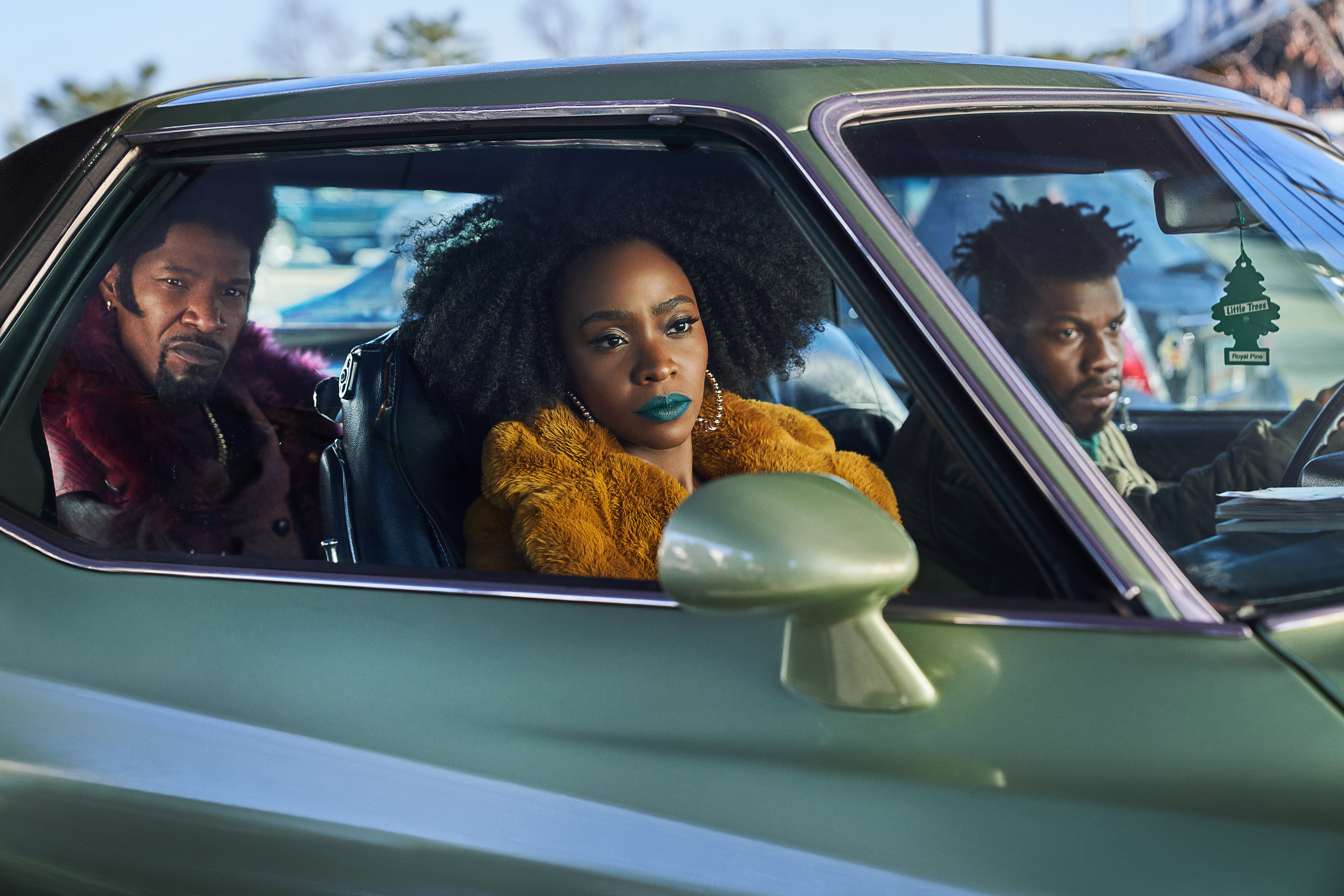 Jamie Foxx as Slick Charles, Teyonah Parris as Yo-Yo, and John Boyega as Fontaine, all sitting in a car in They Cloned Tyrone.