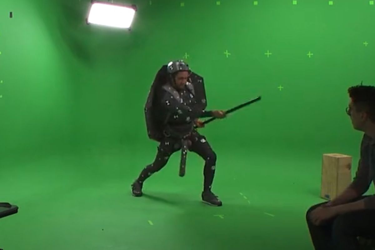 A man in a ninja turtle motion capture suit swings his weapon while a phallus bean bag prop hangs between his legs